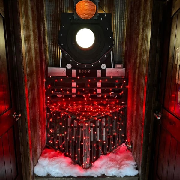 A train engine decoration with red lights and artificial snow, flanked by wooden doors.
