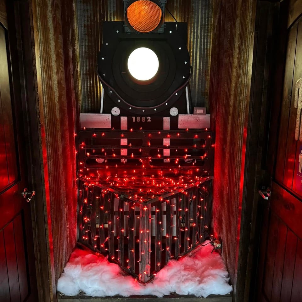 A train engine decoration with red lights and artificial snow, flanked by wooden doors.