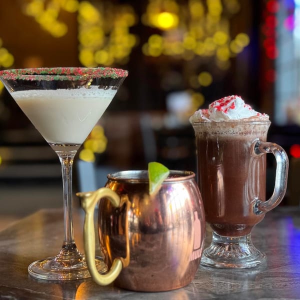 Three festive drinks: a martini, a Moscow mule, and a hot chocolate with whipped cream.