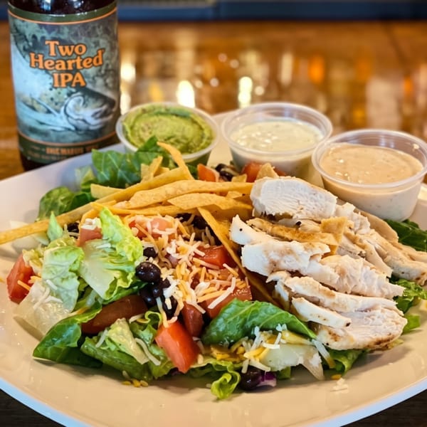 Chicken taco salad with guacamole, two dressings, and a bottle of Two Hearted IPA.