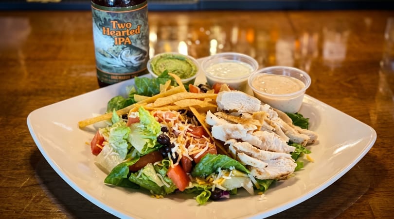 Chicken taco salad with guacamole, two dressings, and a bottle of Two Hearted IPA.