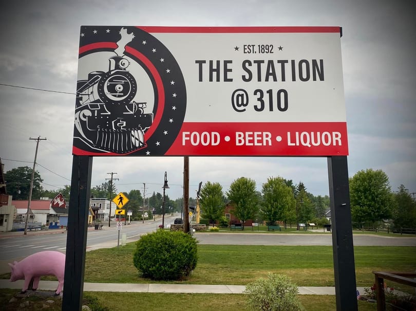 A large sign for "The Station @ 310" restaurant, featuring a train logo, food, beer, and liquor.