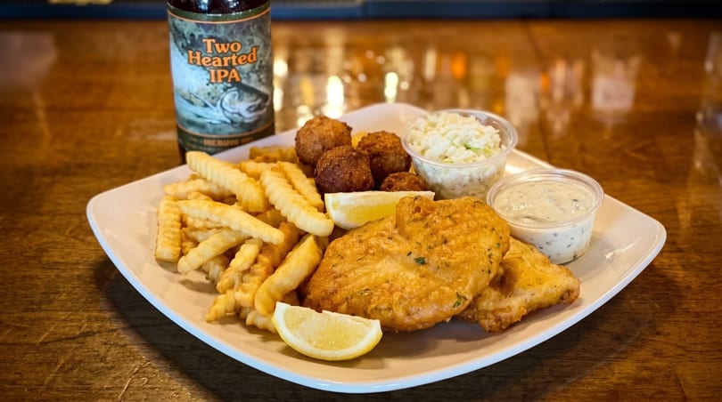 Fish and chips with hush puppies, coleslaw, tartar sauce, lemon, and a bottle of Two Hearted IPA.